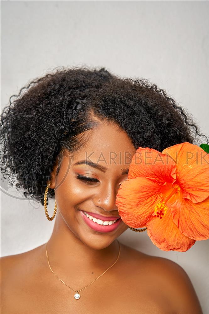 Jeune caribéenne souriante avec une fleur