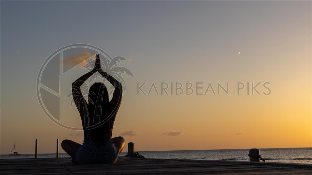 Jeune femme en position de yoga au coucher de soleil