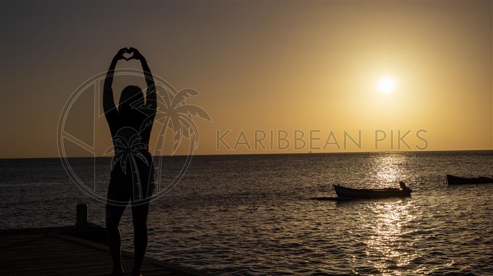 Silhouette de femme avec un cœur au coucher de soleil